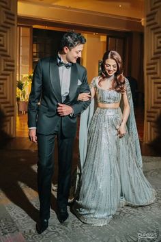 a man in a tuxedo standing next to a woman in a silver dress