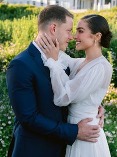 a bride and groom embracing each other in front of flowers