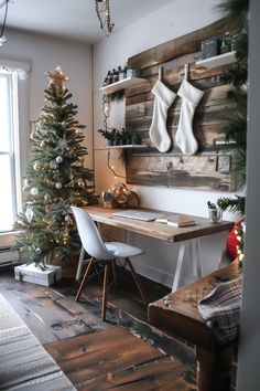 a christmas tree is sitting in front of a desk with two stockings hanging on the wall