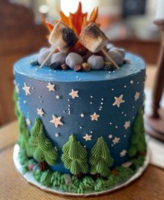 a blue cake with two birds sitting on top of it, surrounded by stars and trees