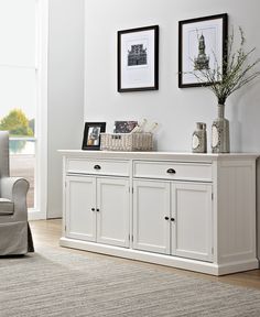 a living room with white furniture and two pictures on the wall above it's dresser