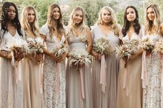 a group of women standing next to each other wearing dresses and holding bouquets in their hands