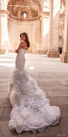 a woman in a wedding dress standing on the floor with her arms behind her back