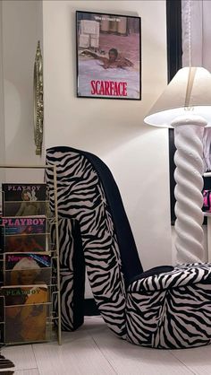 a zebra print chair sitting in front of a lamp and bookshelf on the floor