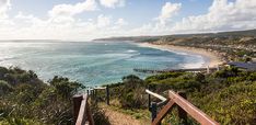 stairs lead down to the beach and ocean from an overlook point on a sunny day