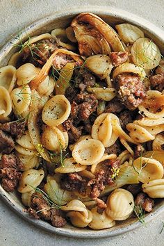 a bowl filled with pasta and meat on top of a table