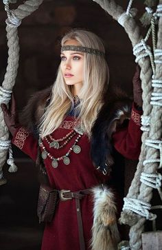 a woman in a red dress and fur stoler standing next to a rope structure