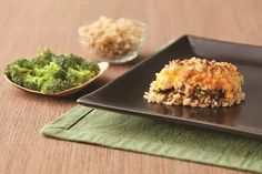 a black plate topped with rice and broccoli on top of a wooden table