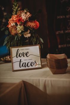 a wooden sign sitting on top of a table next to a vase filled with flowers