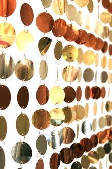 a close up of many different colored circles on a white wall with beads hanging from them