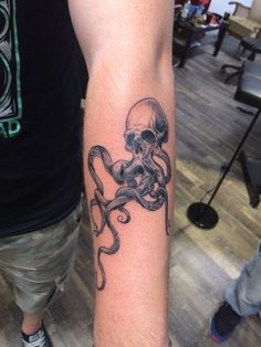 a man with a tattoo on his arm has an octopus in the shape of a skull