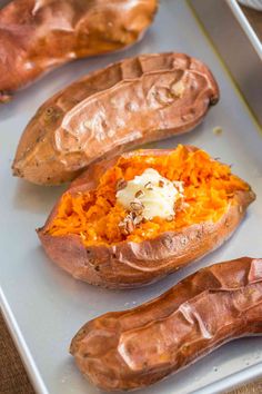 baked sweet potatoes on a baking sheet ready to be cooked in the oven with butter