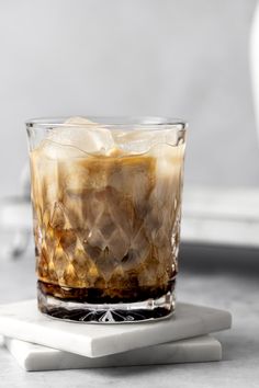 an iced drink in a glass on top of a white coaster with ice cubes