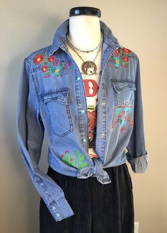 Denim dream with this darling embroidered western shirt! Denim Embroidered Shirt with Turquoise Snaps Cute back yoke detail Cotton Fall Medium Wash Tops With Floral Embroidery, Fall Medium Wash Top With Floral Embroidery, Medium Wash Floral Embroidery Top For Fall, Medium Wash Floral Embroidered Tops For Fall, Embroidered Button-up Western Tops, Western Style Embroidered Button-up Top, Blue Western Tops For Rodeo, Blue Denim Festival Top, Blue Denim Tops For Festival