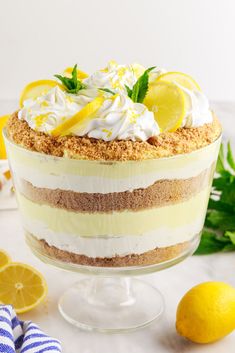 there is a cake with lemons and whipped cream on top in a glass dish