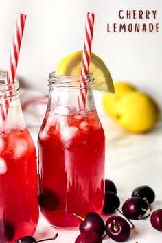 two mason jars filled with cherry lemonade next to fresh cherries and lemon wedges