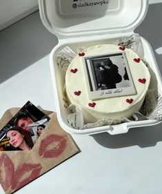 a cake in a white box with red hearts on it and an image of a kissing couple