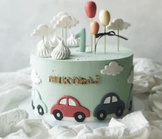 a birthday cake with cars and balloons on the top is decorated in pastel colors