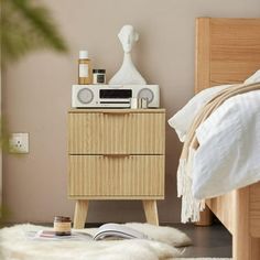 a bedroom with a bed, nightstand and radio on top of the night stand in front of it