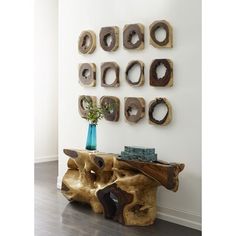 a wooden table sitting in front of a wall filled with different pieces of art on it