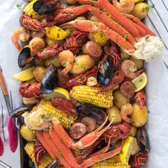 lobsters, corn on the cob and potatoes are served in a roasting pan