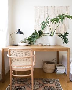 a wooden desk topped with potted plants next to a chair and rug on top of a hard wood floor