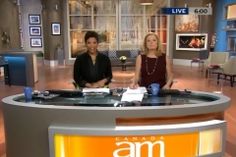 two women sitting at a table on an am news set