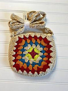 a crocheted bag hanging on the wall with a bow tie around it's neck