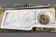 an old white sink on the ground next to a metal grate