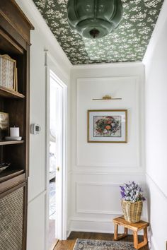 the hallway is decorated in white and green with floral wallpaper on the ceiling, along with a wooden bench