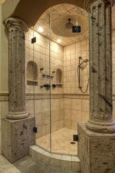 a walk in shower sitting next to a stone pillar and tiled floored area with columns