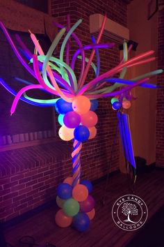 balloons and streamers in the shape of an umbrella stand against a brick wall at night