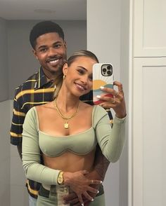 a man and woman taking a selfie in the mirror