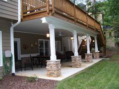 a covered patio with stone pillars and steps leading up to the upper level of the house