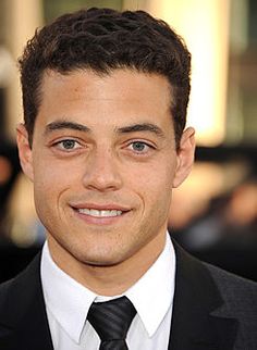 a man in a suit and tie smiling at the camera with his eyes wide open