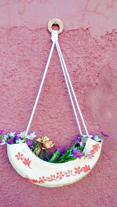 a hanging planter filled with flowers on a pink wall