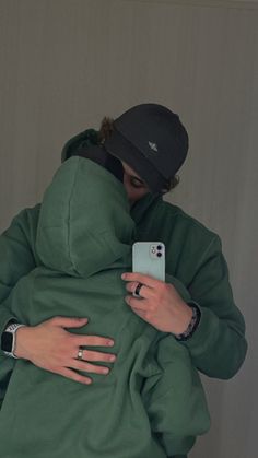 a person in a green hoodie holding a cell phone