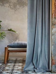 an open curtain in front of a chair and potted plant on the floor next to it