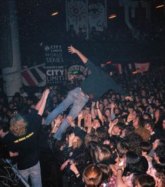 a group of people at a concert with their arms in the air and one person jumping up into the air