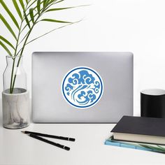 a laptop computer sitting on top of a desk next to a vase with a plant