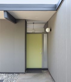 a yellow door is in the middle of an empty room with gravel on the ground