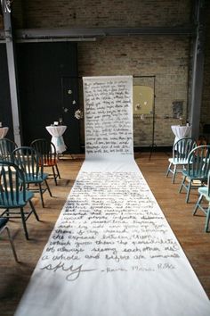 a long table with chairs and writing on the back wall is set up for an event