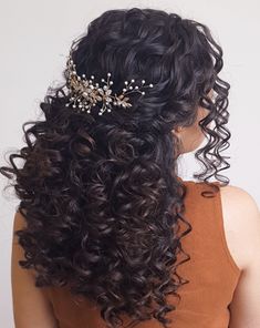 the back of a woman's head with long curly hair and a tiara