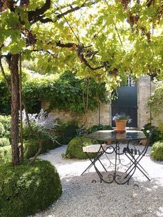 an outdoor table and chairs in the middle of a garden