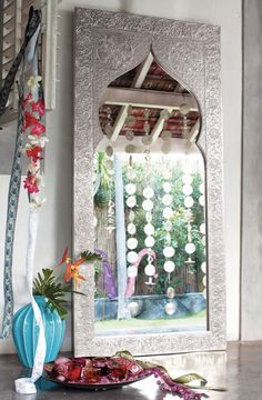 a decorative mirror sitting on top of a table next to a vase filled with flowers