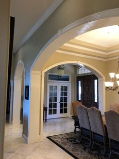 a dining room table and chairs in front of a doorway with an archway leading into the kitchen