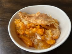 a bowl filled with food sitting on top of a wooden table next to a fork