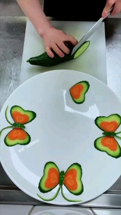 a person cutting cucumbers on a plate with oranges and green leaves painted on them