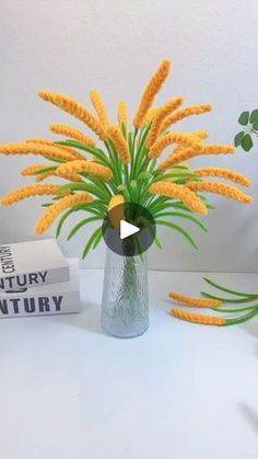 a vase filled with yellow flowers sitting on top of a white table next to books