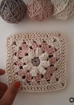 someone is crocheting together to make a square with balls of yarn on it